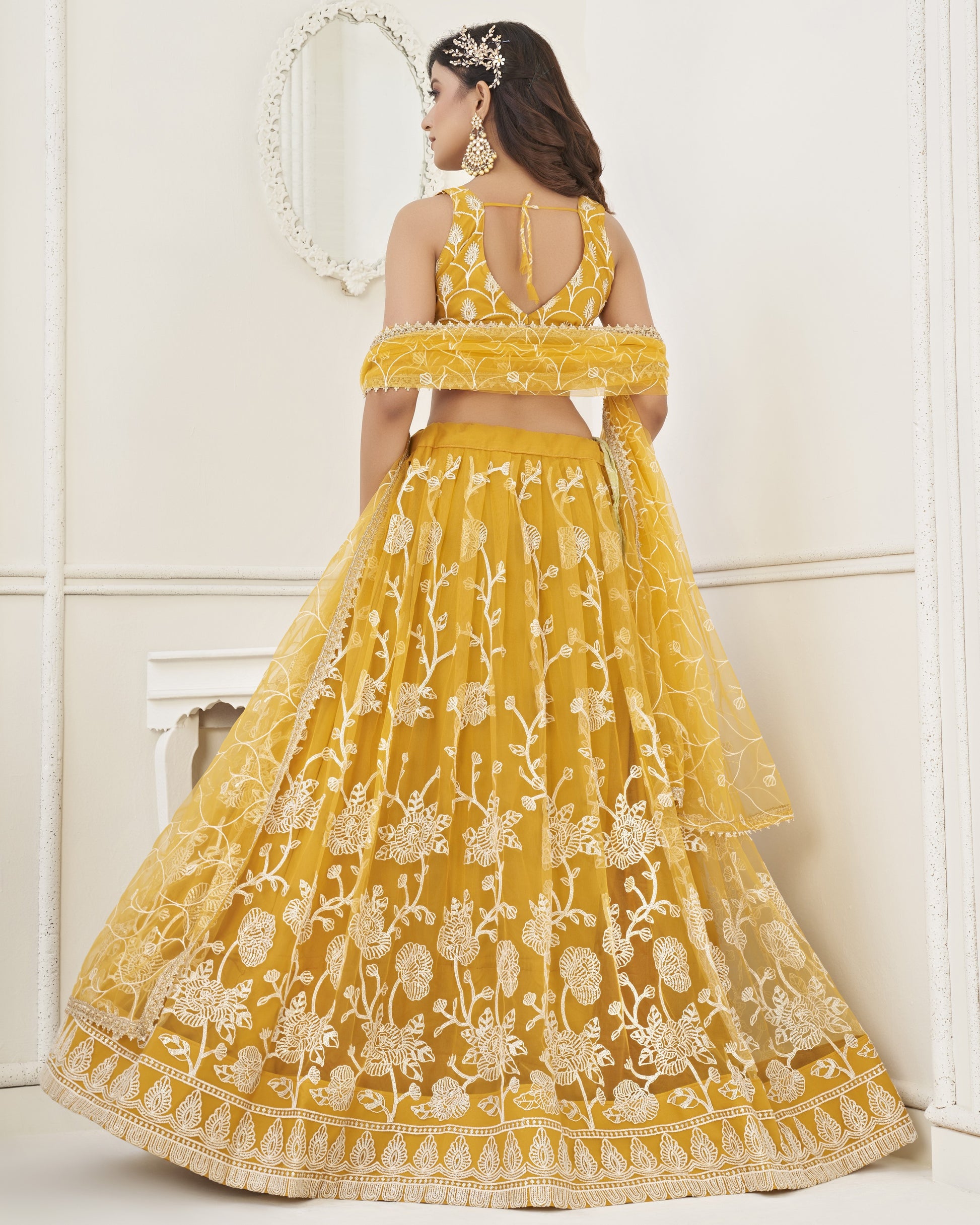 Woman wearing a yellow embroidered lehenga with a white background