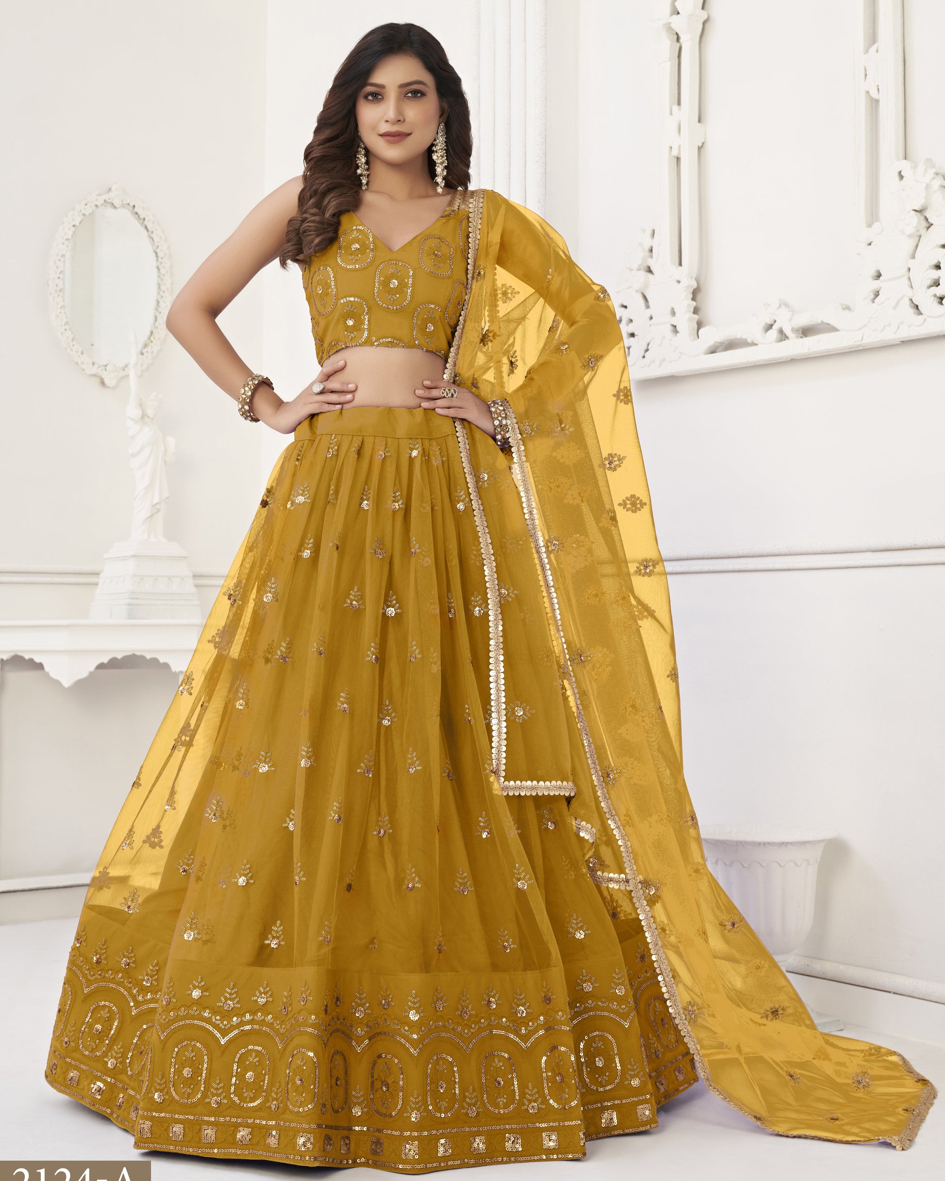 Woman wearing a yellow embroidered lehenga with a white background