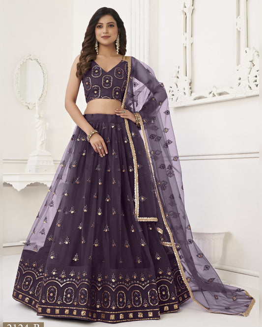 Woman wearing a dark purple embroidered lehenga with a matching dupatta in a white room.