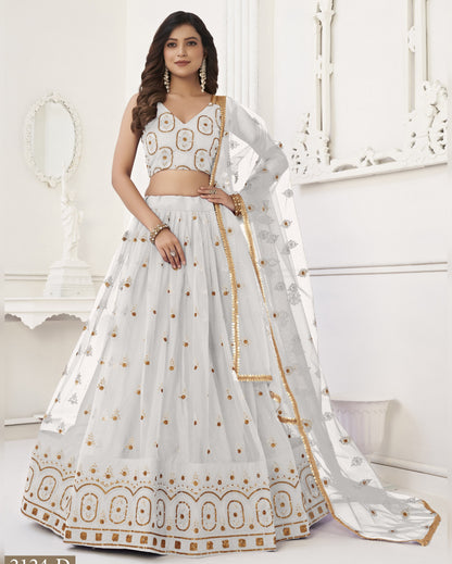 White embroidered lehenga with gold details worn by a model in a white room.