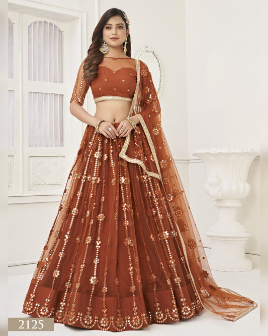 Woman wearing a brown embroidered lehenga with a matching blouse in a white room.