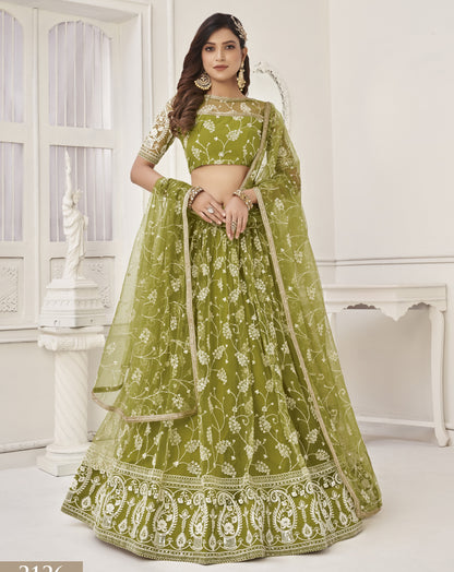 Woman wearing a green embroidered traditional outfit in a white room.