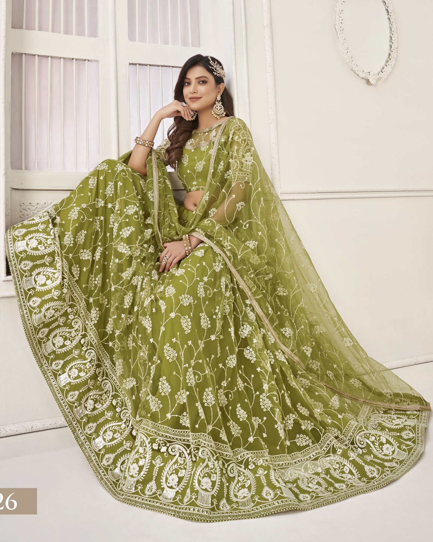 Woman wearing a green embroidered saree with a white background