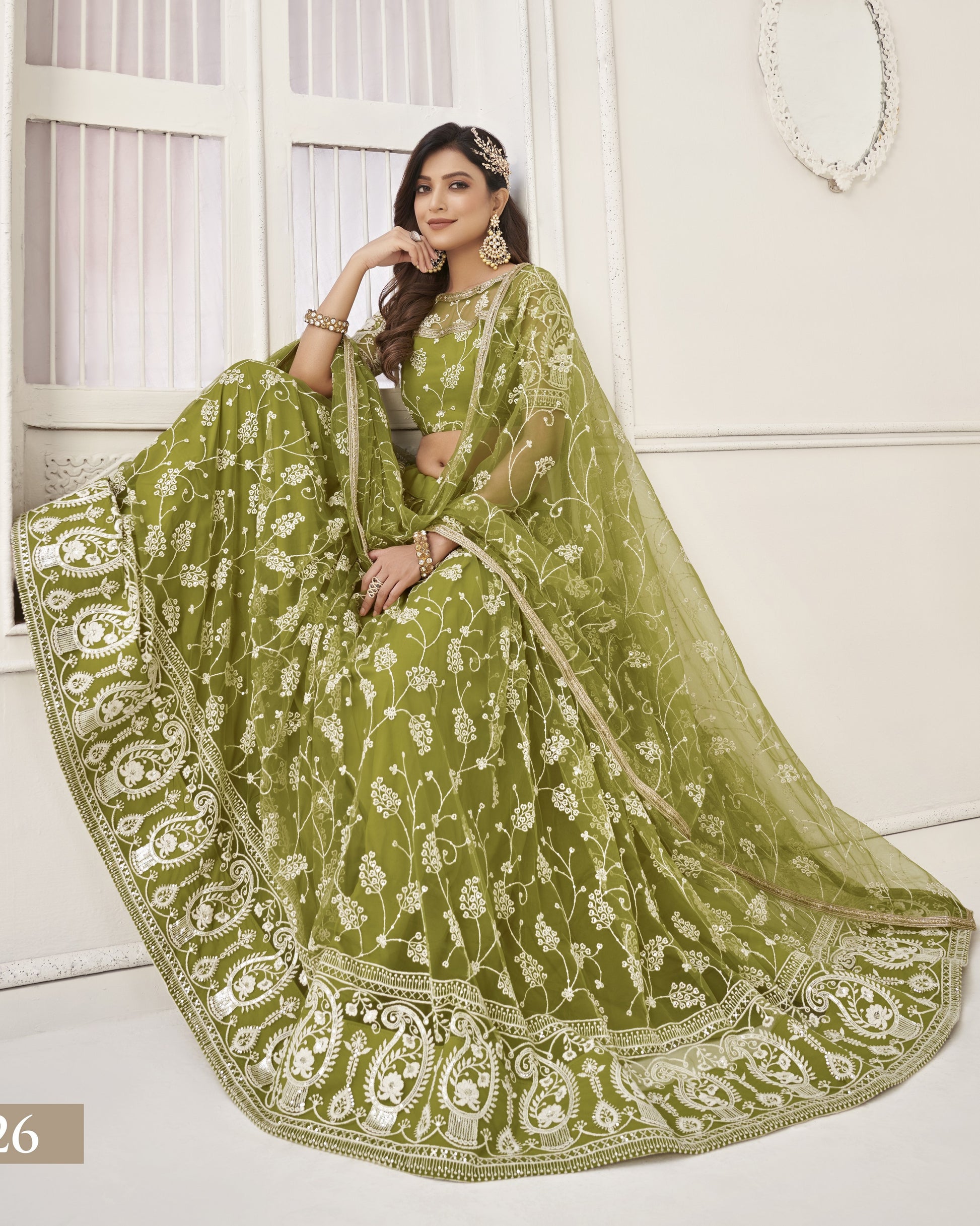 Woman wearing a green embroidered saree with a white background