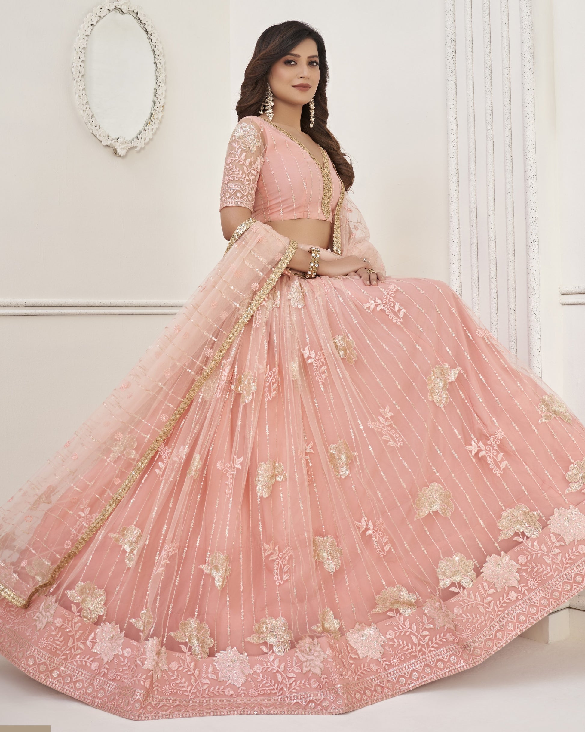Woman wearing a pink embroidered lehenga with a white background