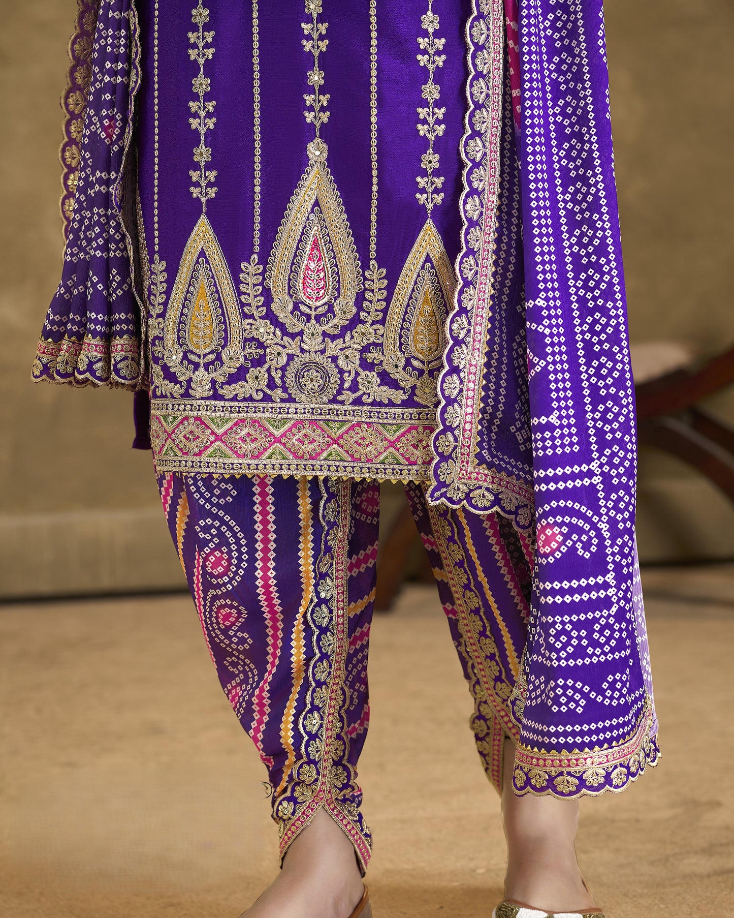 Purple embroidered traditional outfit with gold detailing on a neutral background