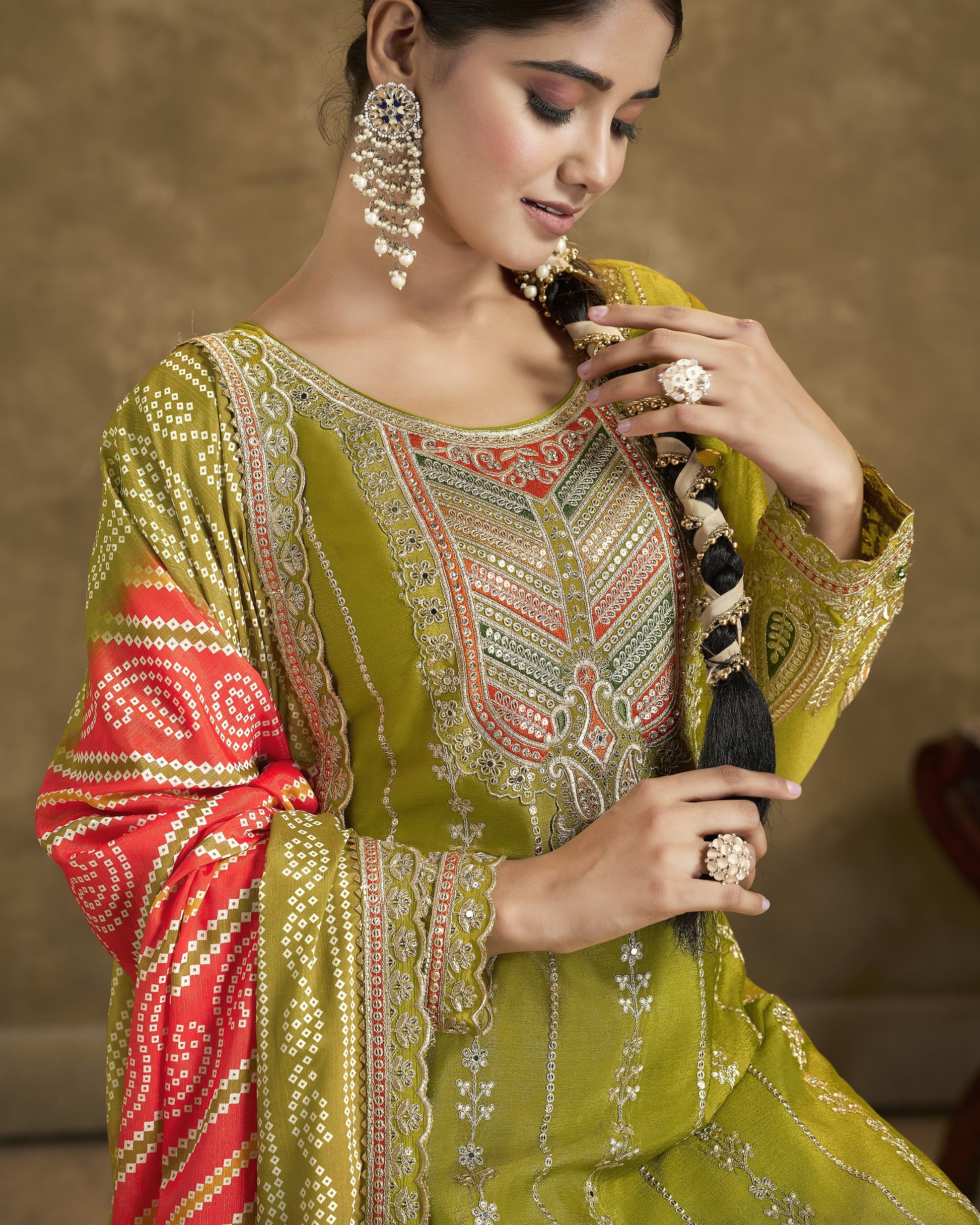 Woman wearing a traditional embroidered outfit with jewelry against a brown background