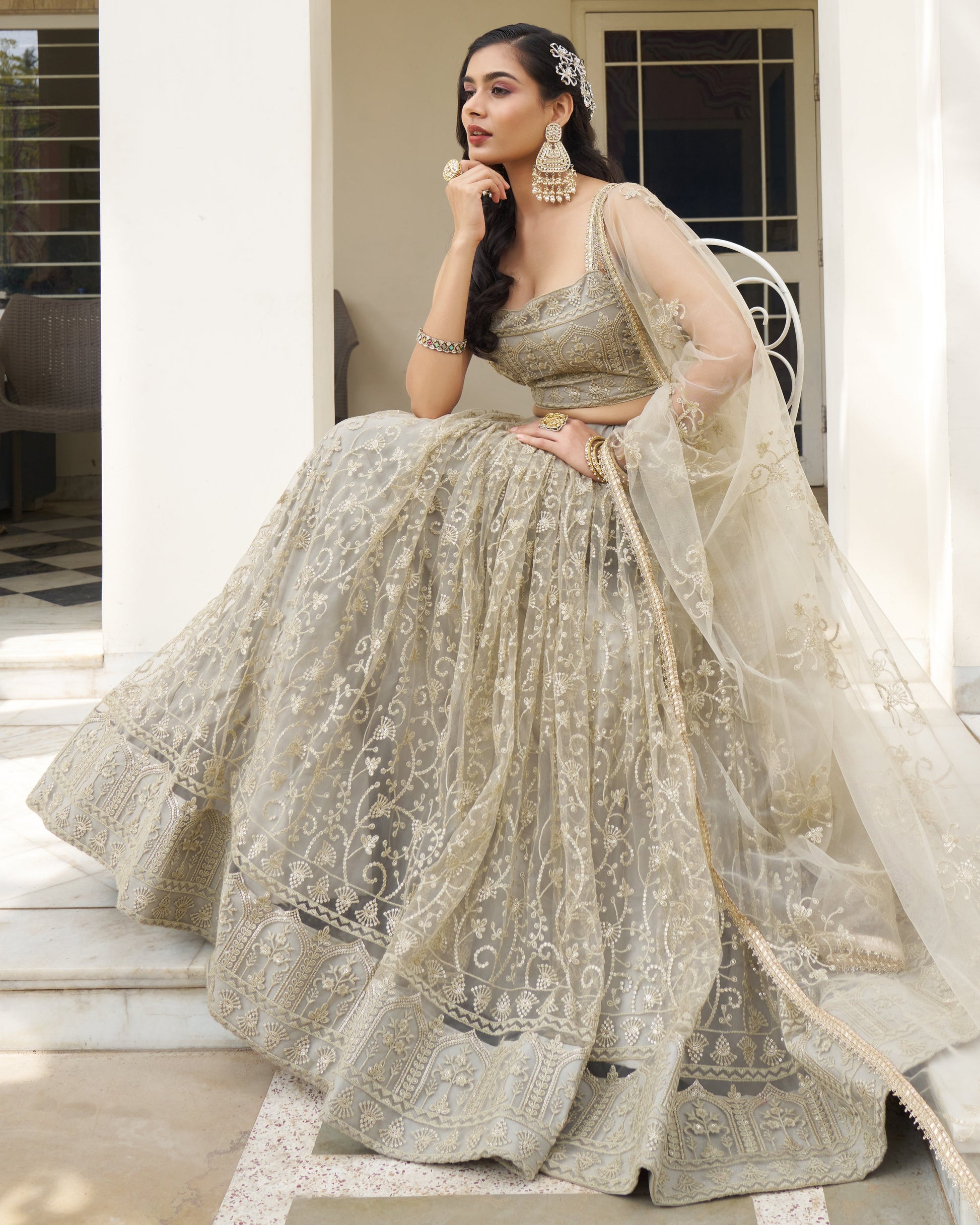 Woman in a traditional embroidered outfit sitting on steps outside a building.