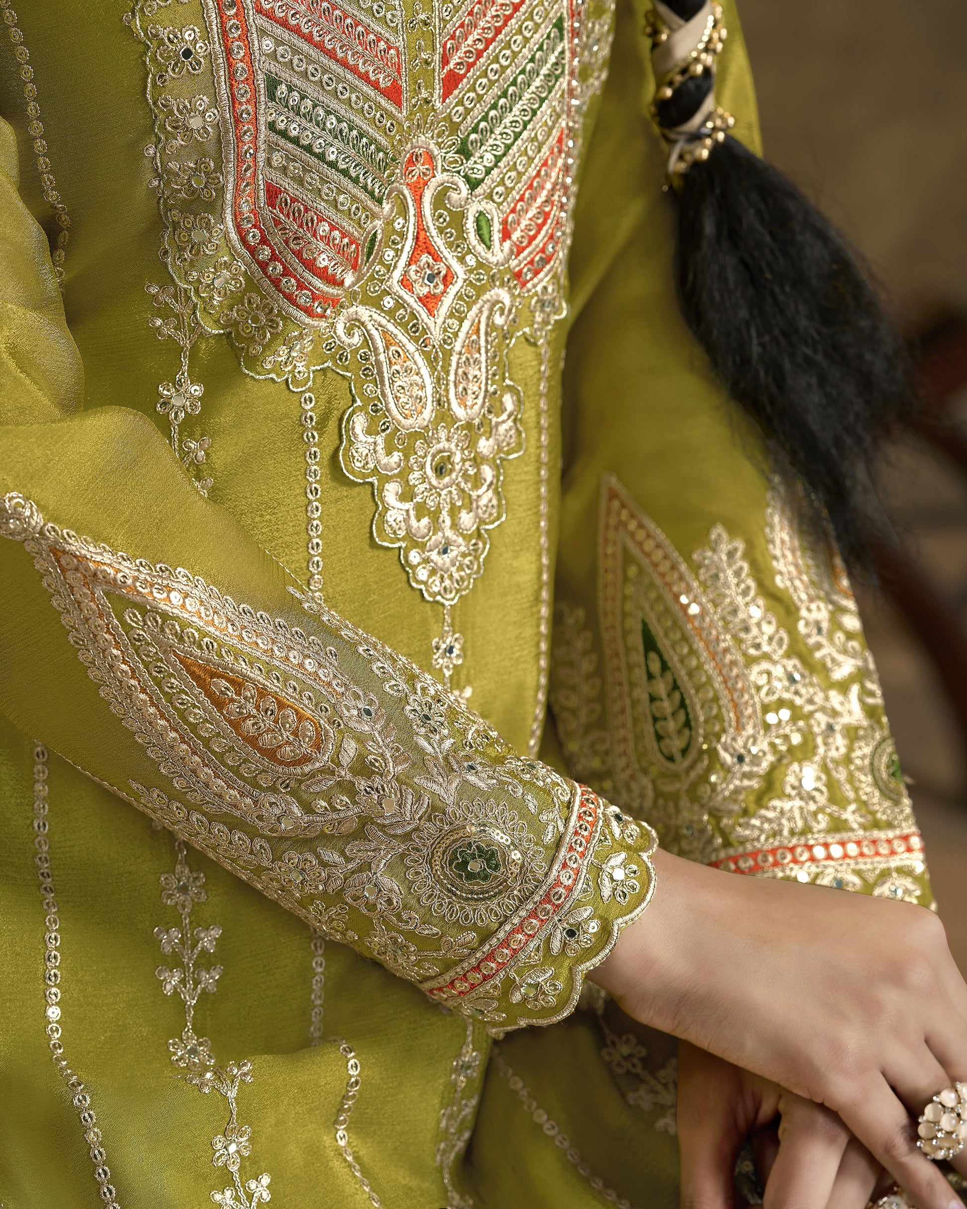 Close-up of a green embroidered garment with intricate patterns