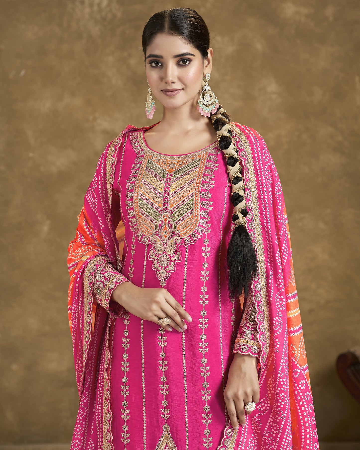 Woman wearing a pink embroidered traditional outfit with a brown background