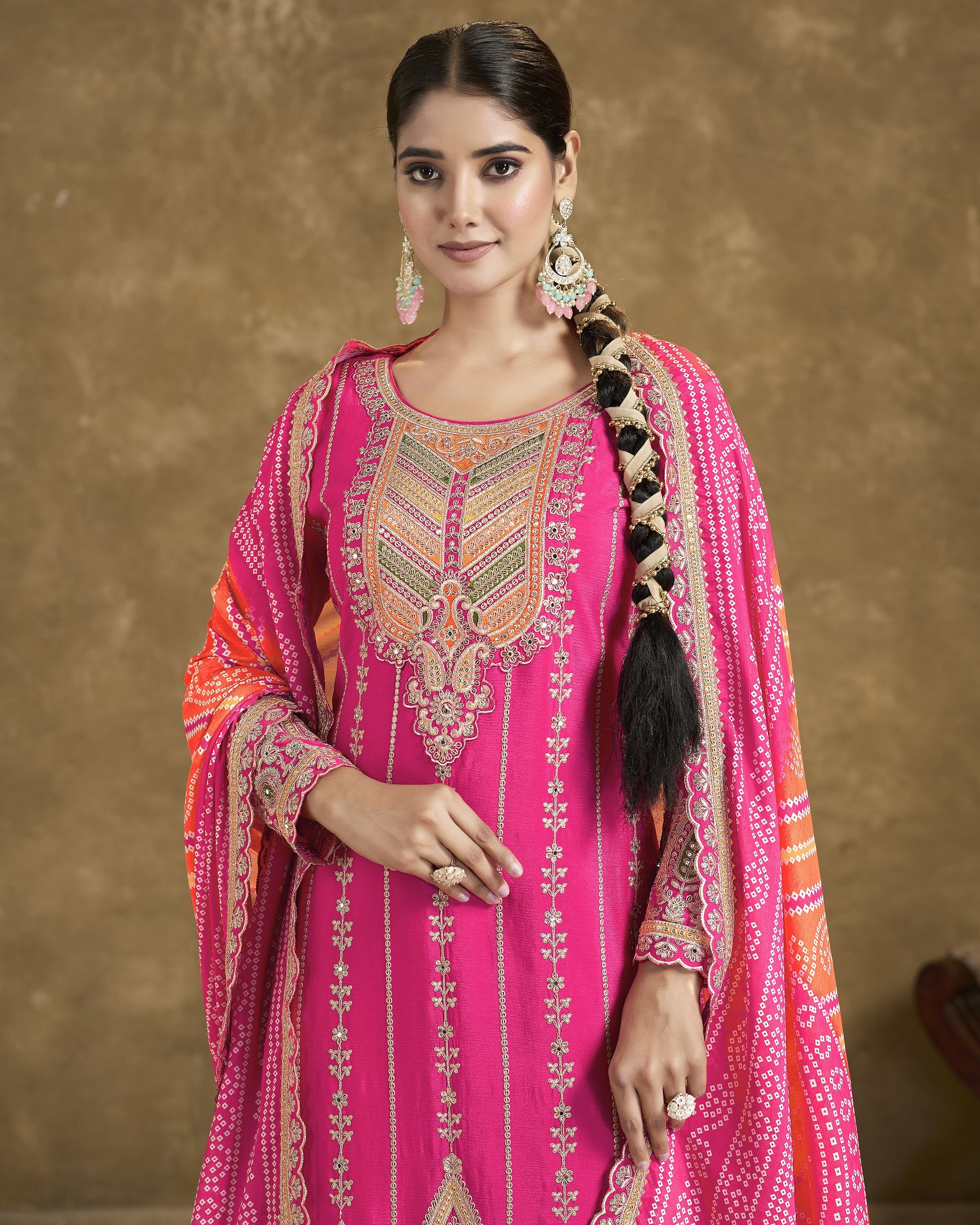 Woman wearing a pink embroidered traditional outfit with a brown background