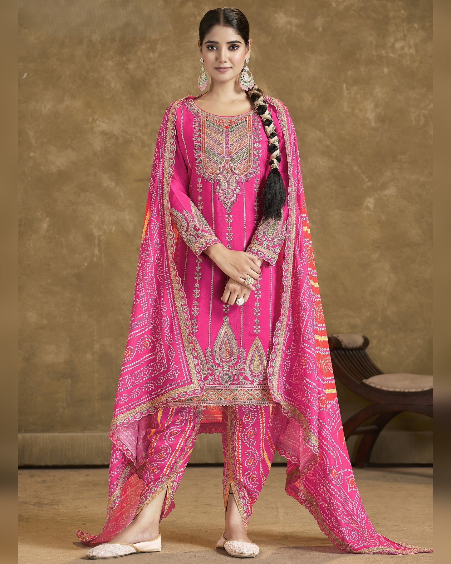 Woman wearing a bright pink traditional outfit with intricate patterns on a brown background