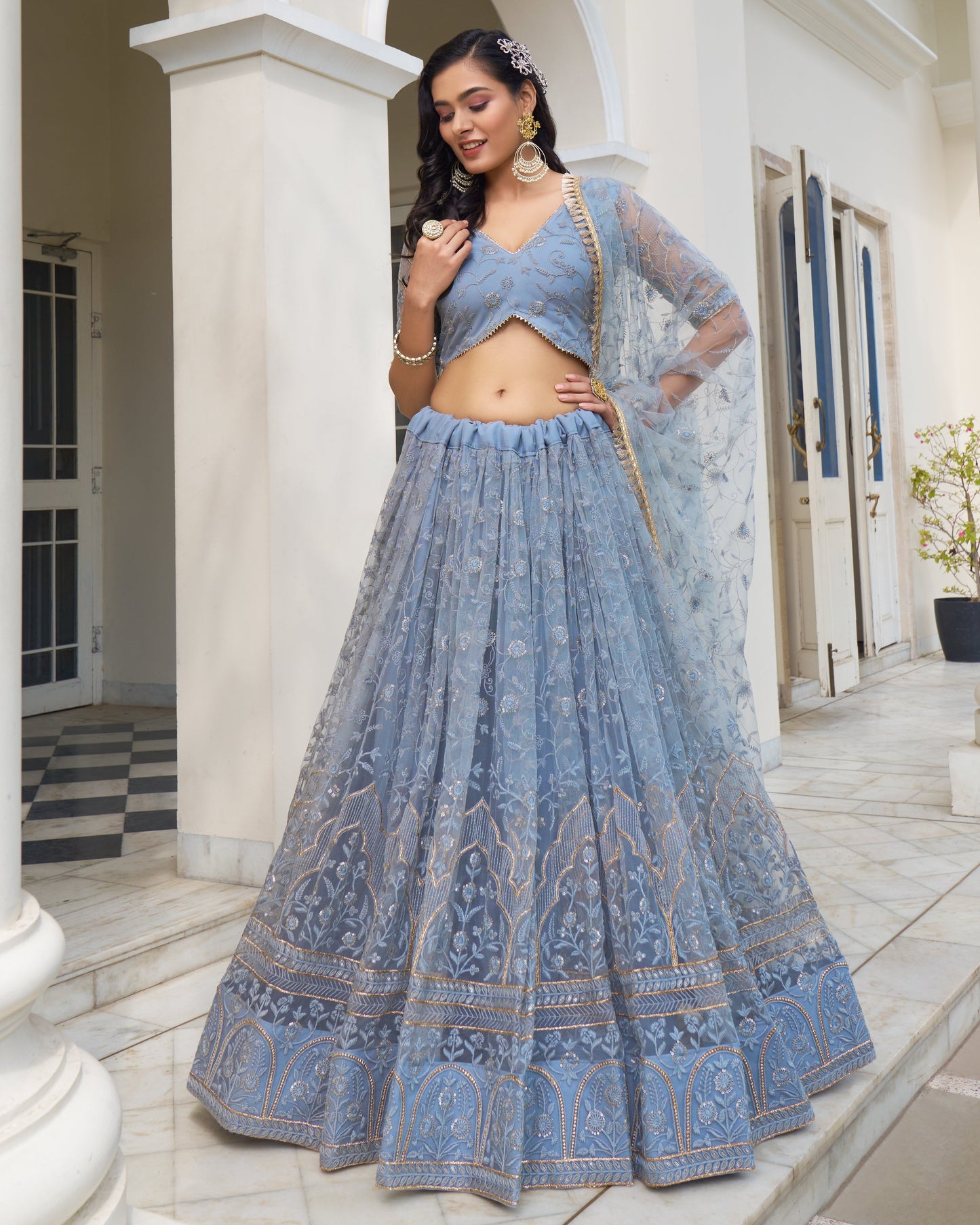 Woman in a blue traditional outfit standing in a well-lit room.