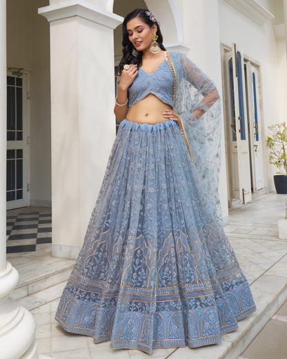 Woman in a blue traditional outfit standing in a well-lit room.
