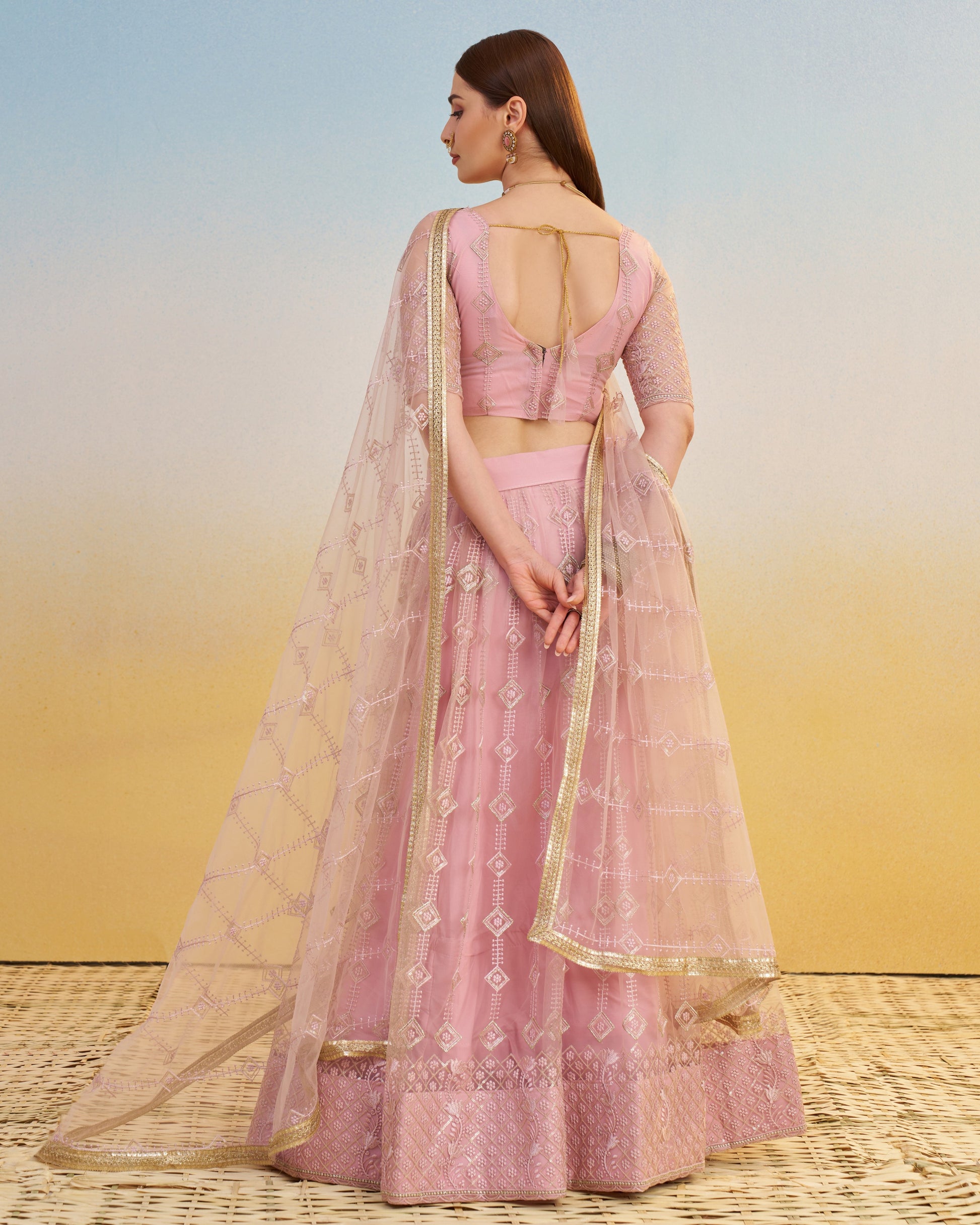 Woman wearing a pink traditional outfit with a sheer dupatta against a gradient background
