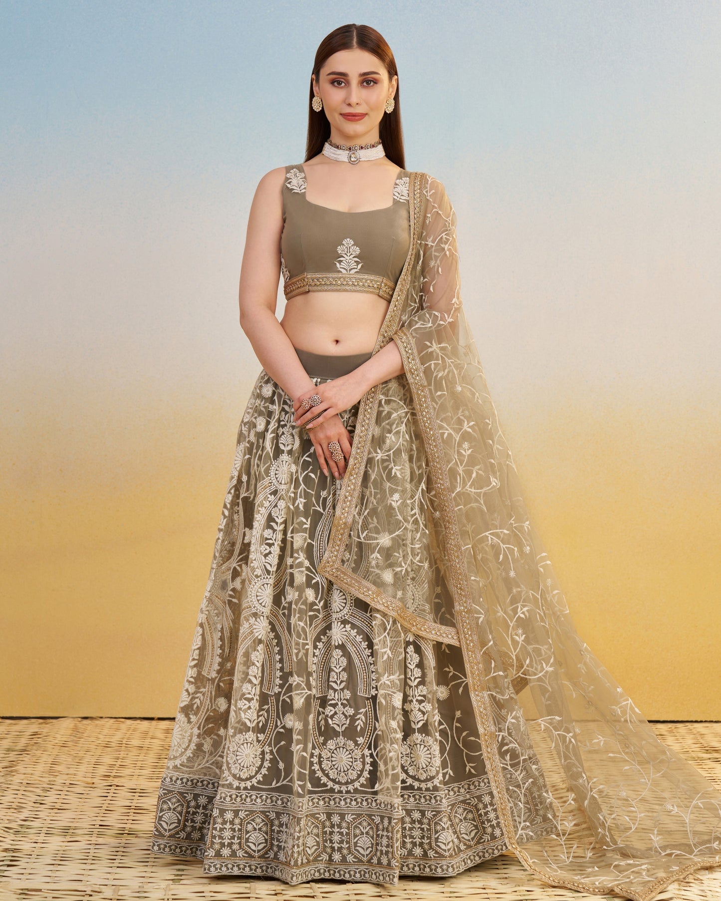 Woman wearing a traditional outfit with a embroidered lehenga and blouse against a gradient background