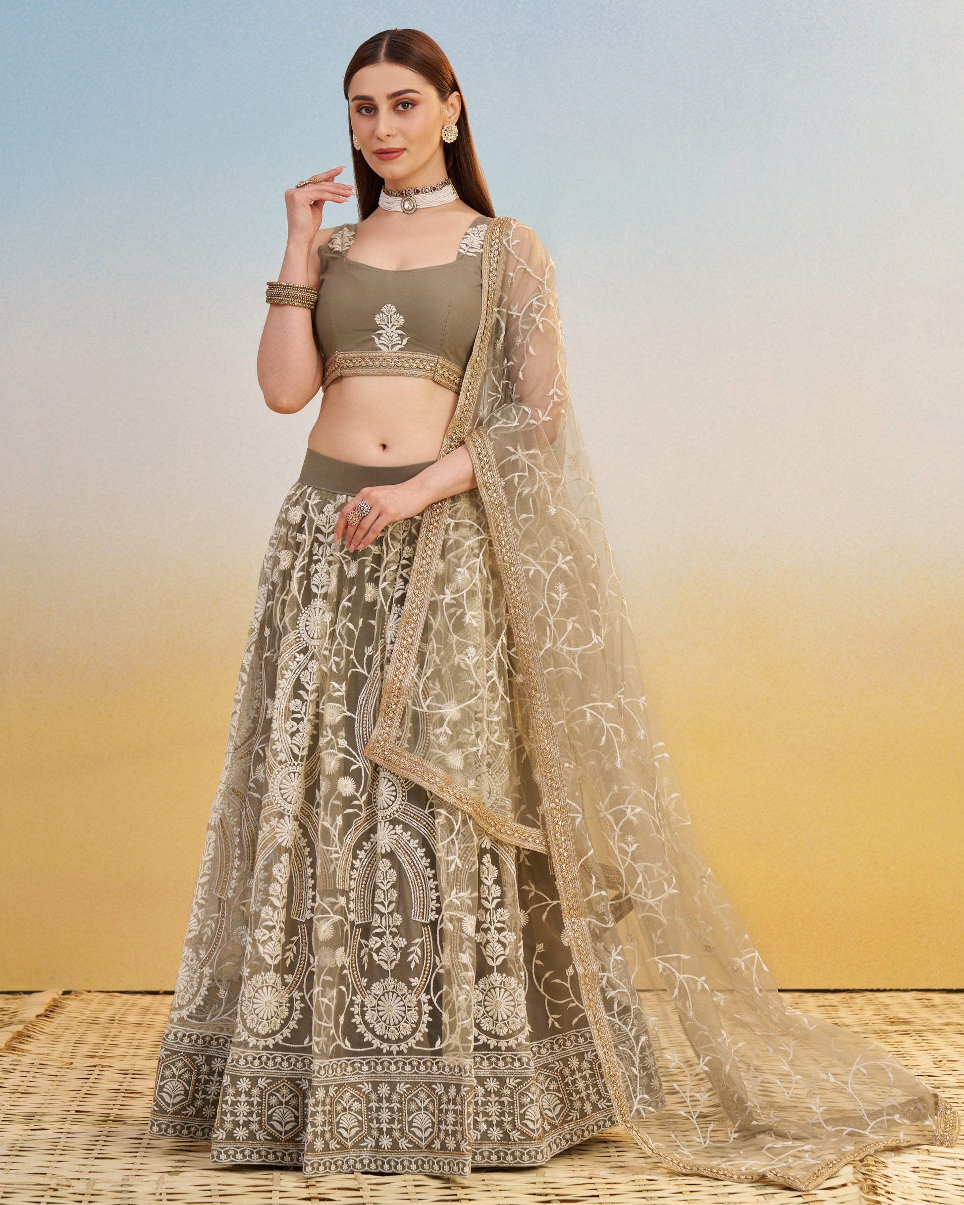 Woman wearing a traditional outfit with a patterned dress and beige dupatta on a gradient background