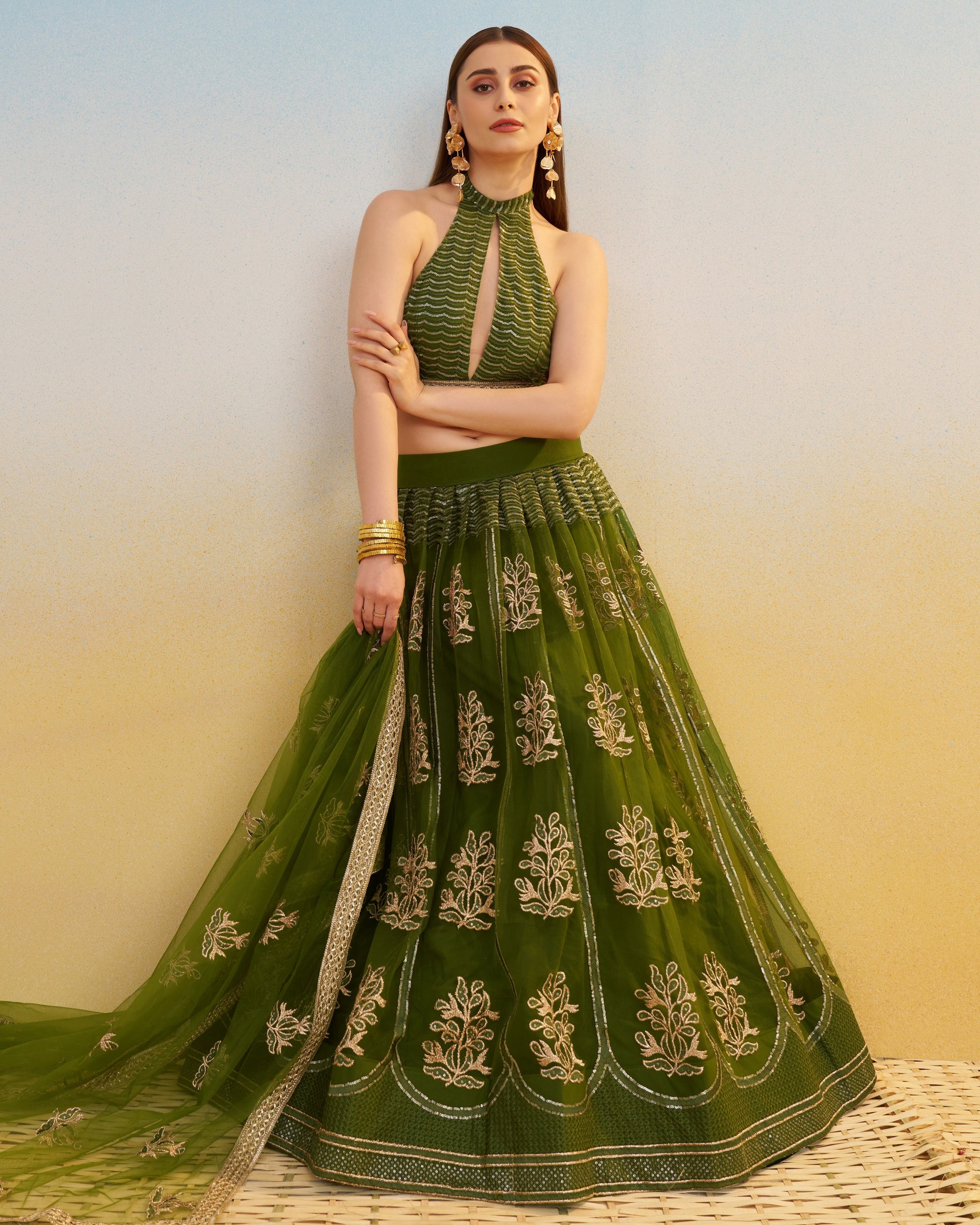Woman wearing a green embroidered traditional outfit with a plain background