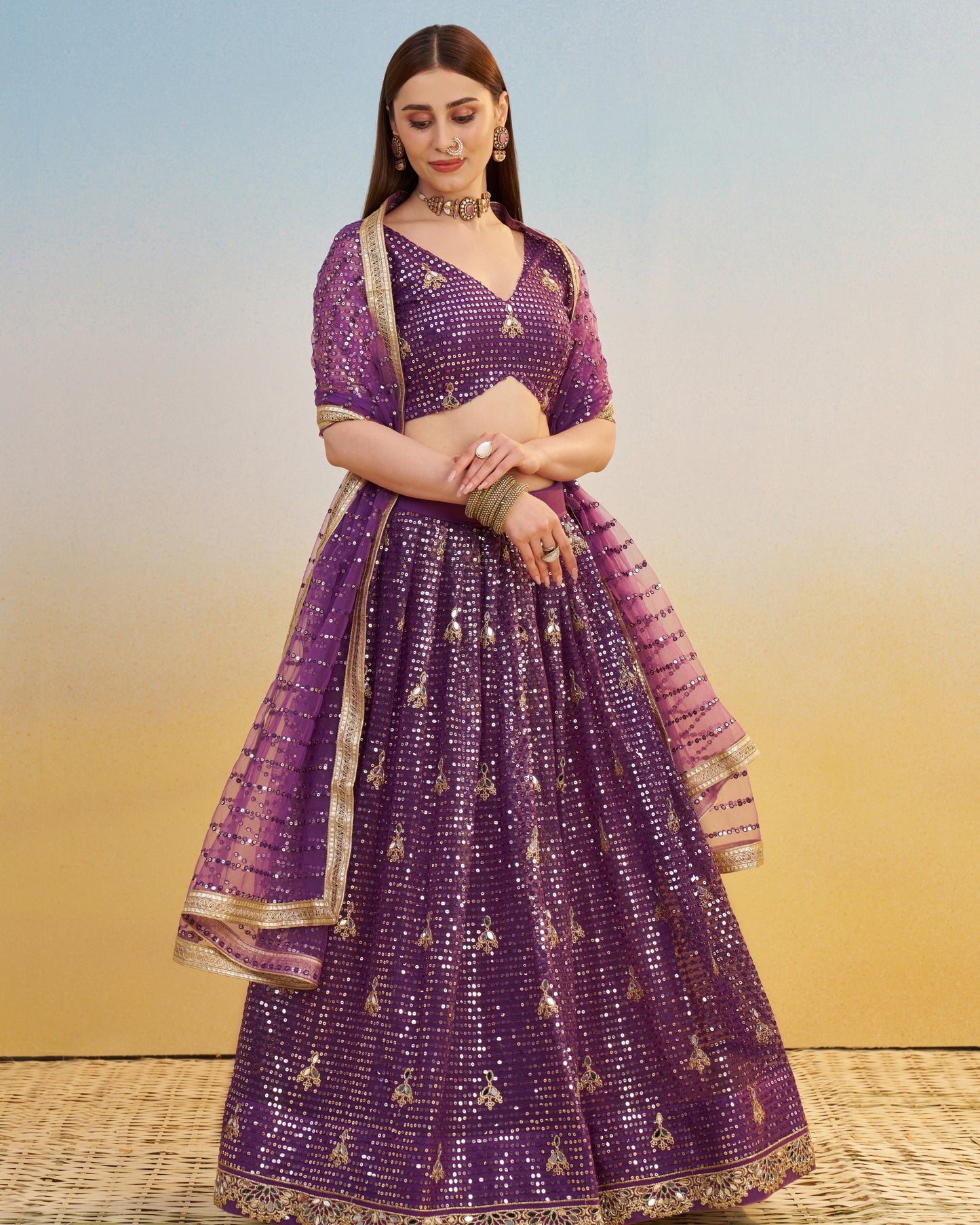 Woman wearing a purple traditional outfit with gold embroidery on a gradient background