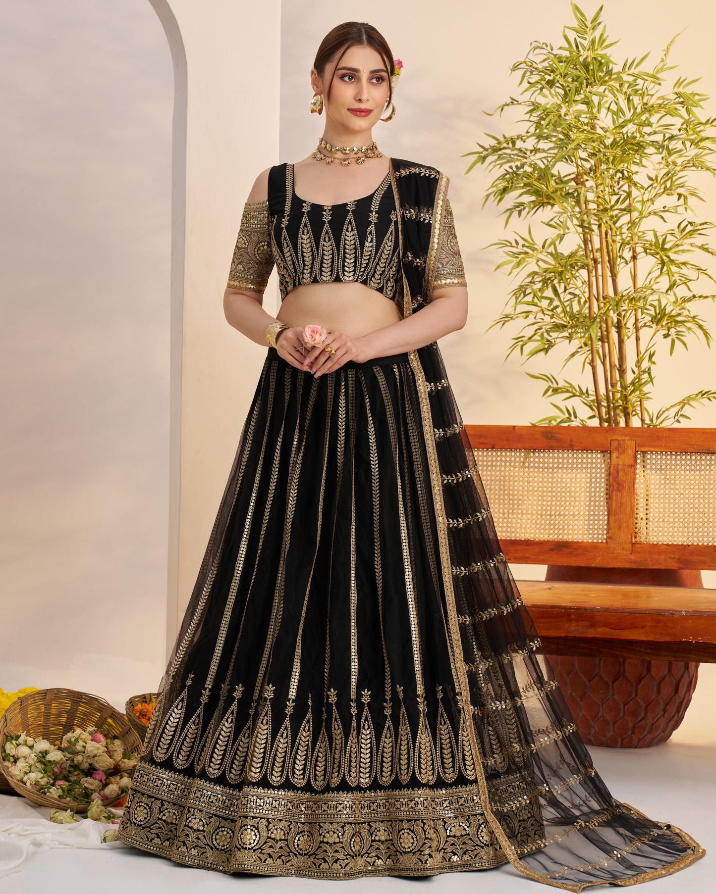 Woman wearing a black and gold embroidered traditional outfit with a plant in the background