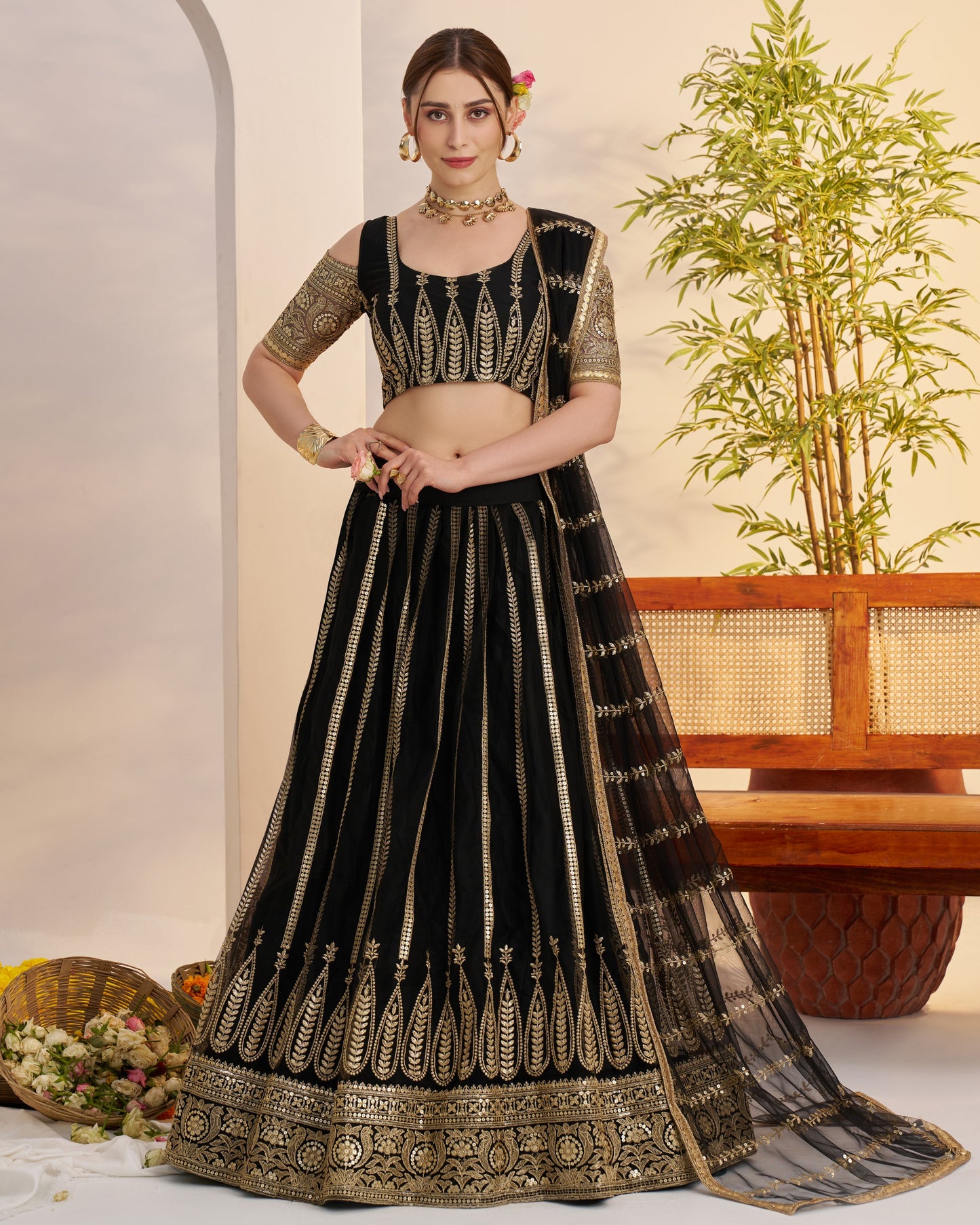 Woman wearing a black and gold embroidered traditional outfit with a plant in the background