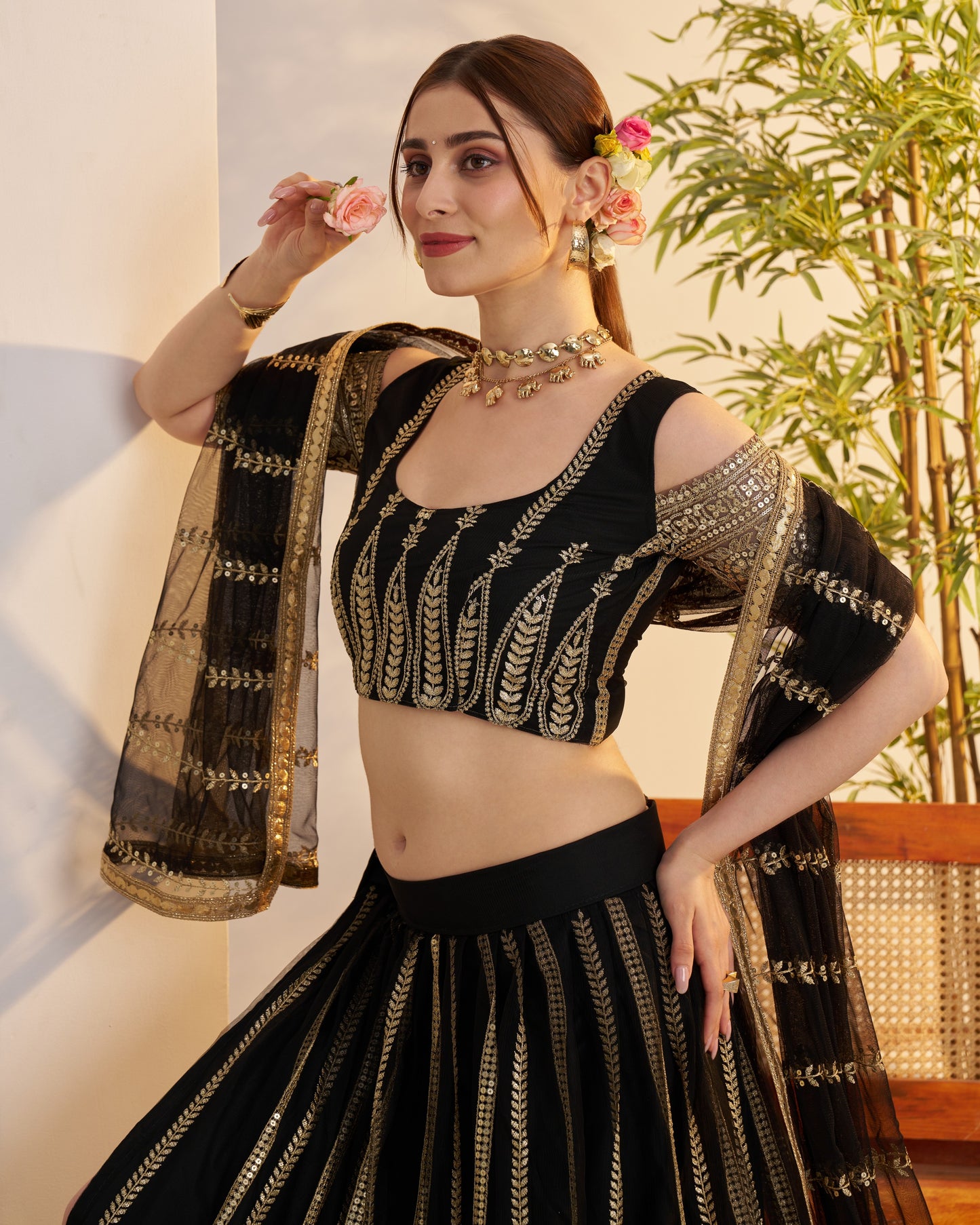 Woman in a black and gold traditional outfit with floral decorations indoors.