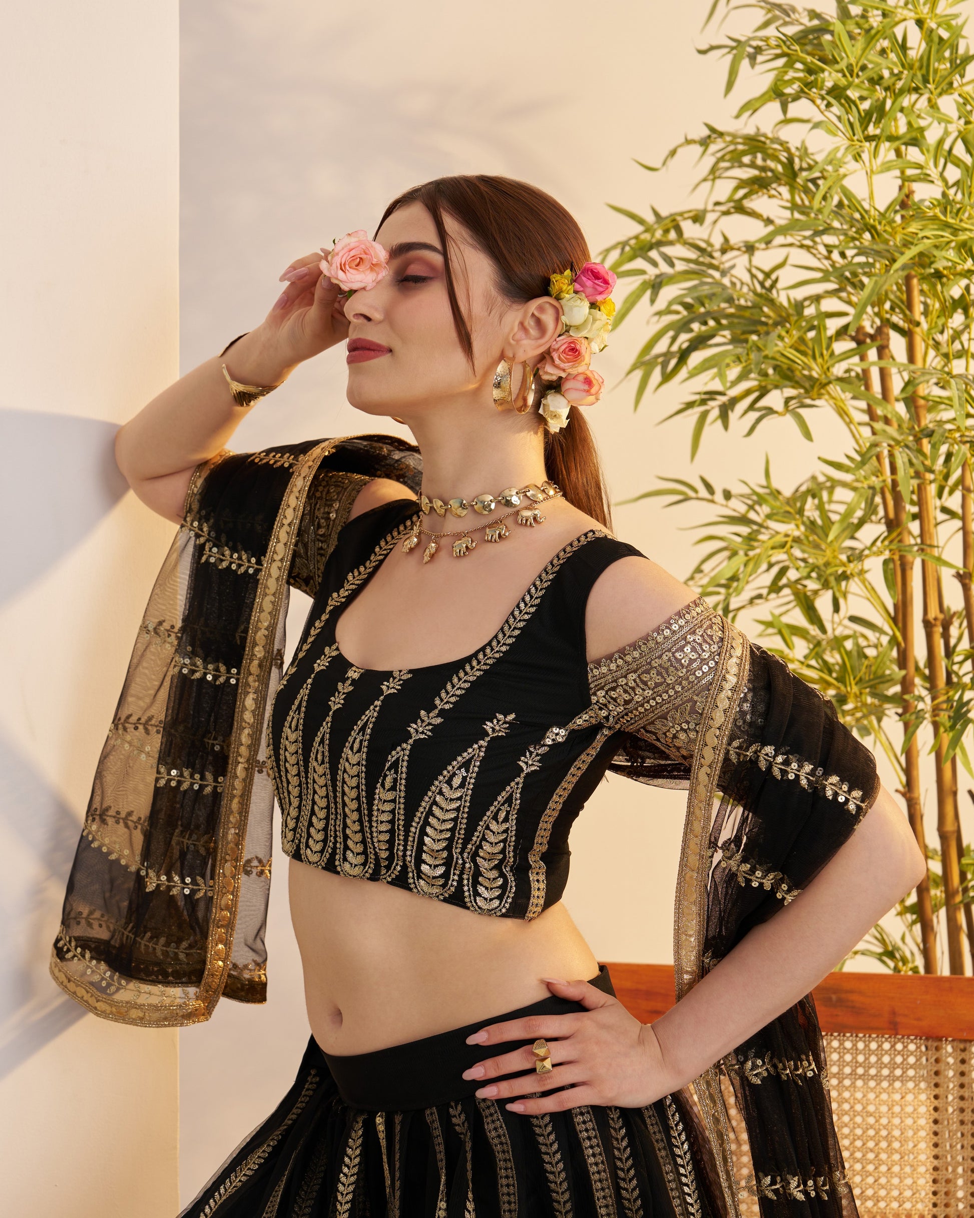 Woman in a black and gold traditional outfit with floral decorations indoors.