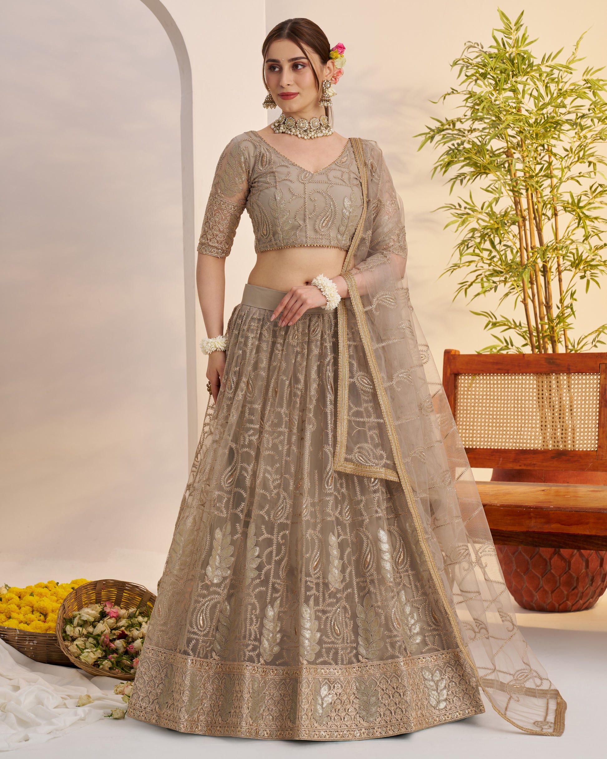 Woman in a traditional outfit with a plant and decorative items in the background