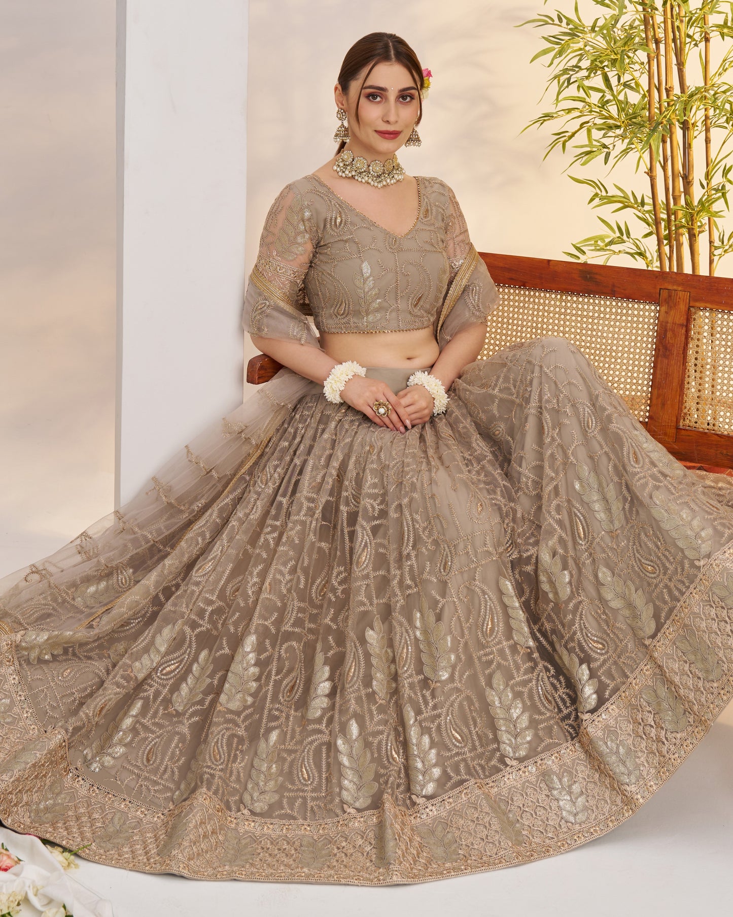 Woman in a traditional embroidered outfit sitting on a chair with a plant in the background