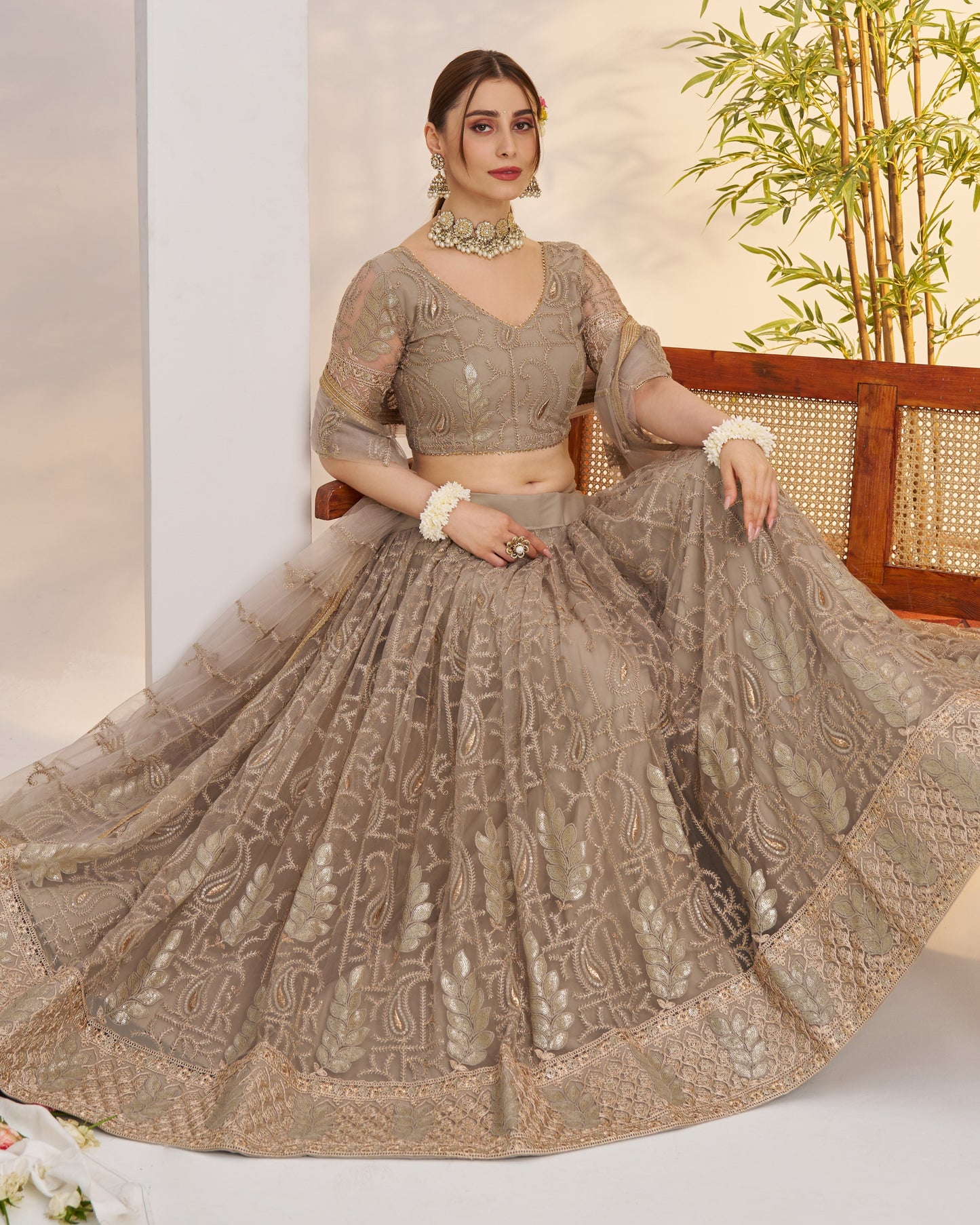 Woman in a traditional outfit with intricate patterns, sitting on a chair.