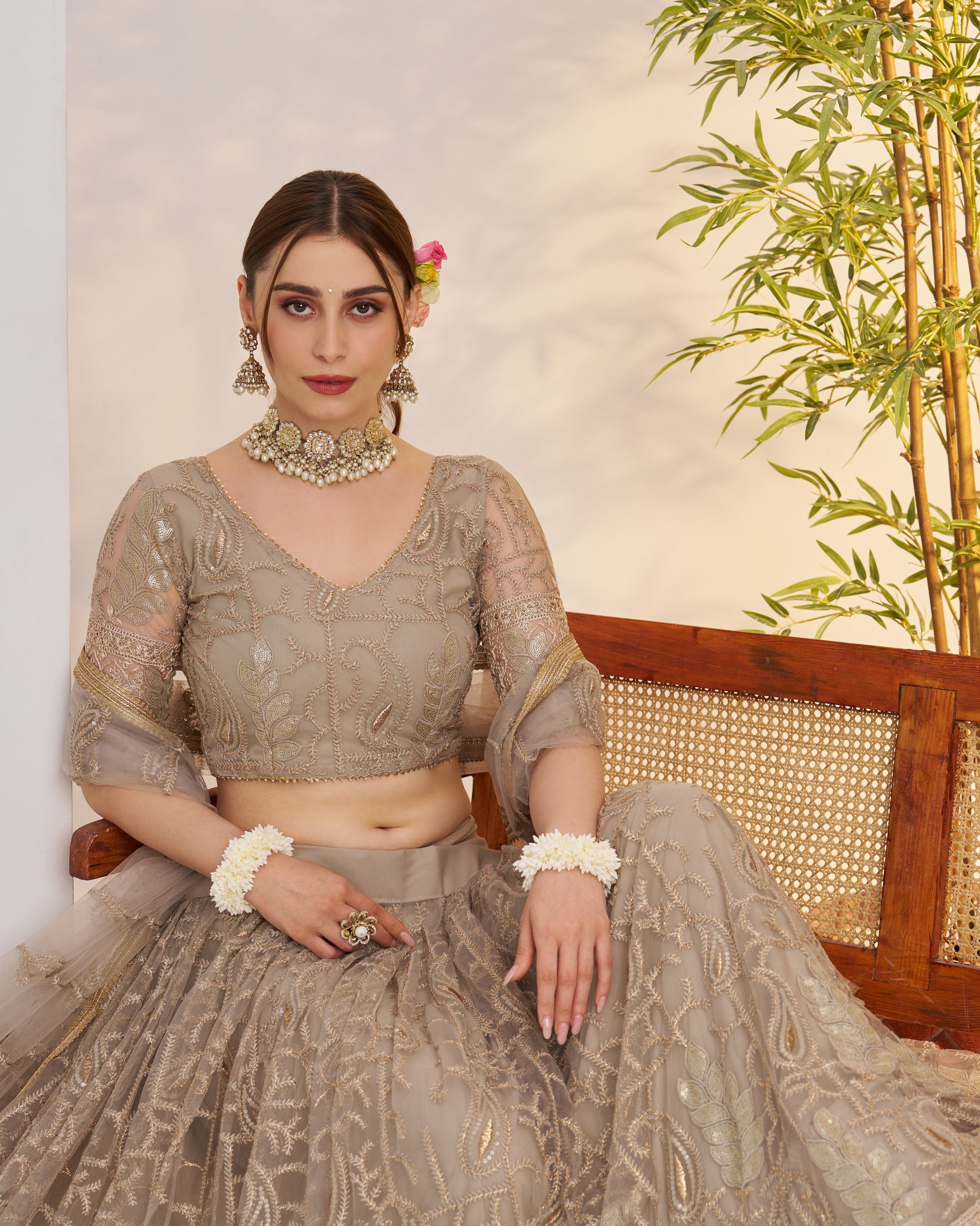 Woman in traditional outfit with intricate patterns sitting on a wooden bench.