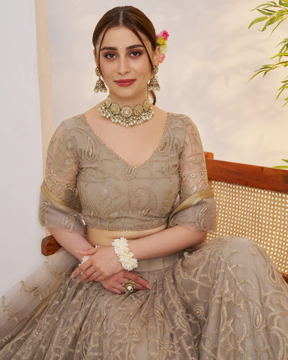 Woman in traditional attire with jewelry, sitting on a chair.