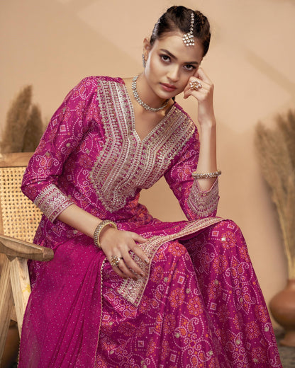 Woman in a traditional pink embroidered outfit sitting on a chair.