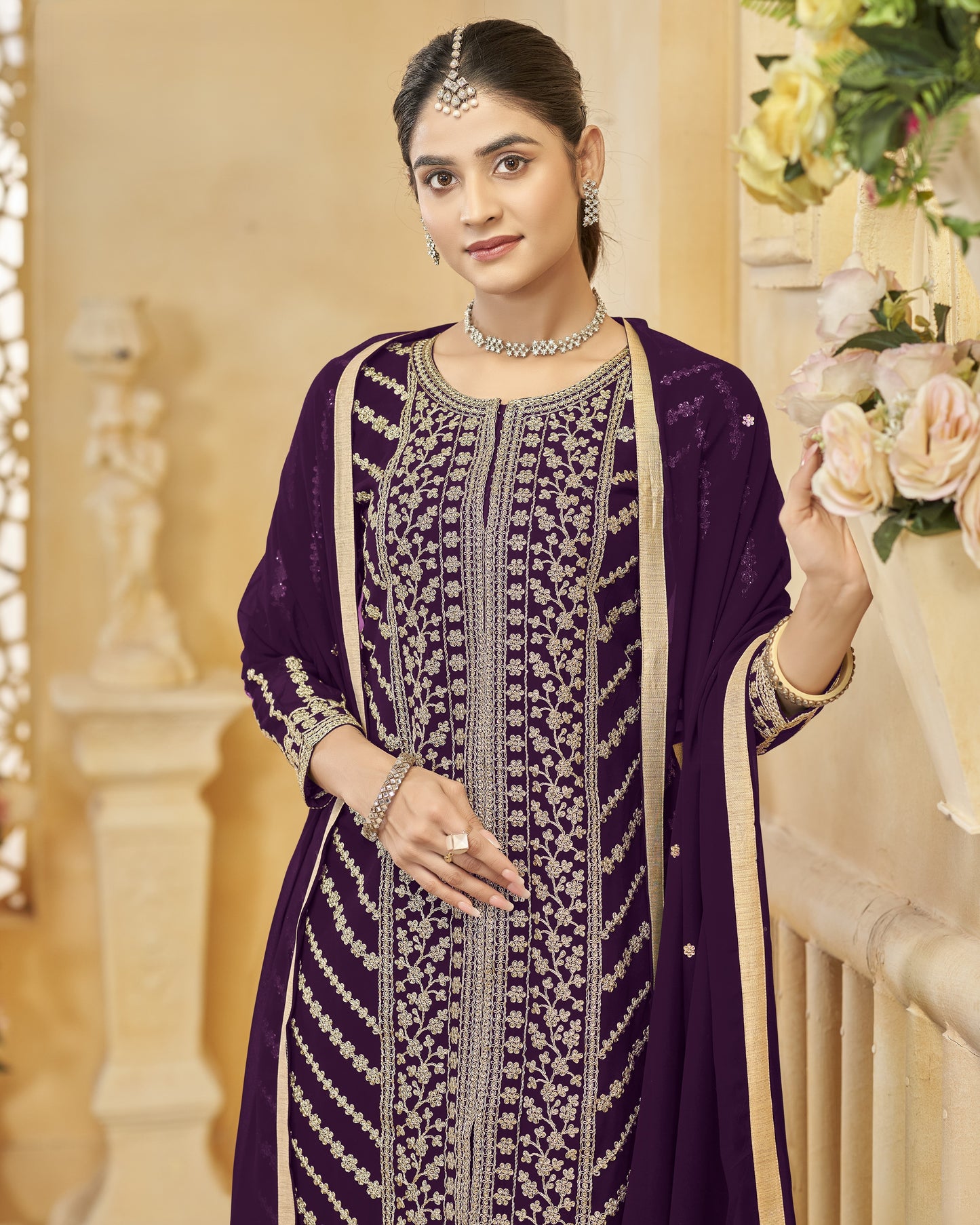 Woman in a purple traditional outfit with floral decorations in the background