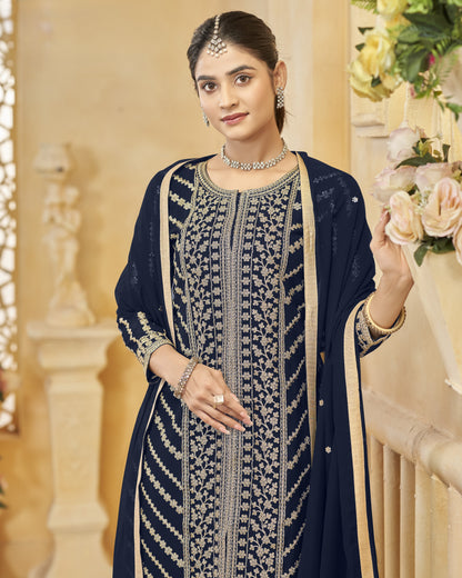 Woman wearing a navy blue embroidered traditional outfit with a beige background