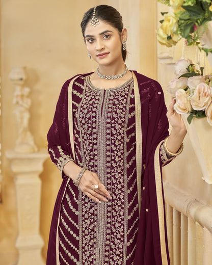 Woman in a traditional embroidered outfit with jewelry, standing indoors.