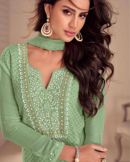 Woman wearing a green embroidered top with a neutral background