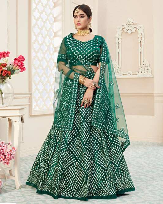 Woman wearing a green and white patterned saree with a matching blouse in an elegant indoor setting.