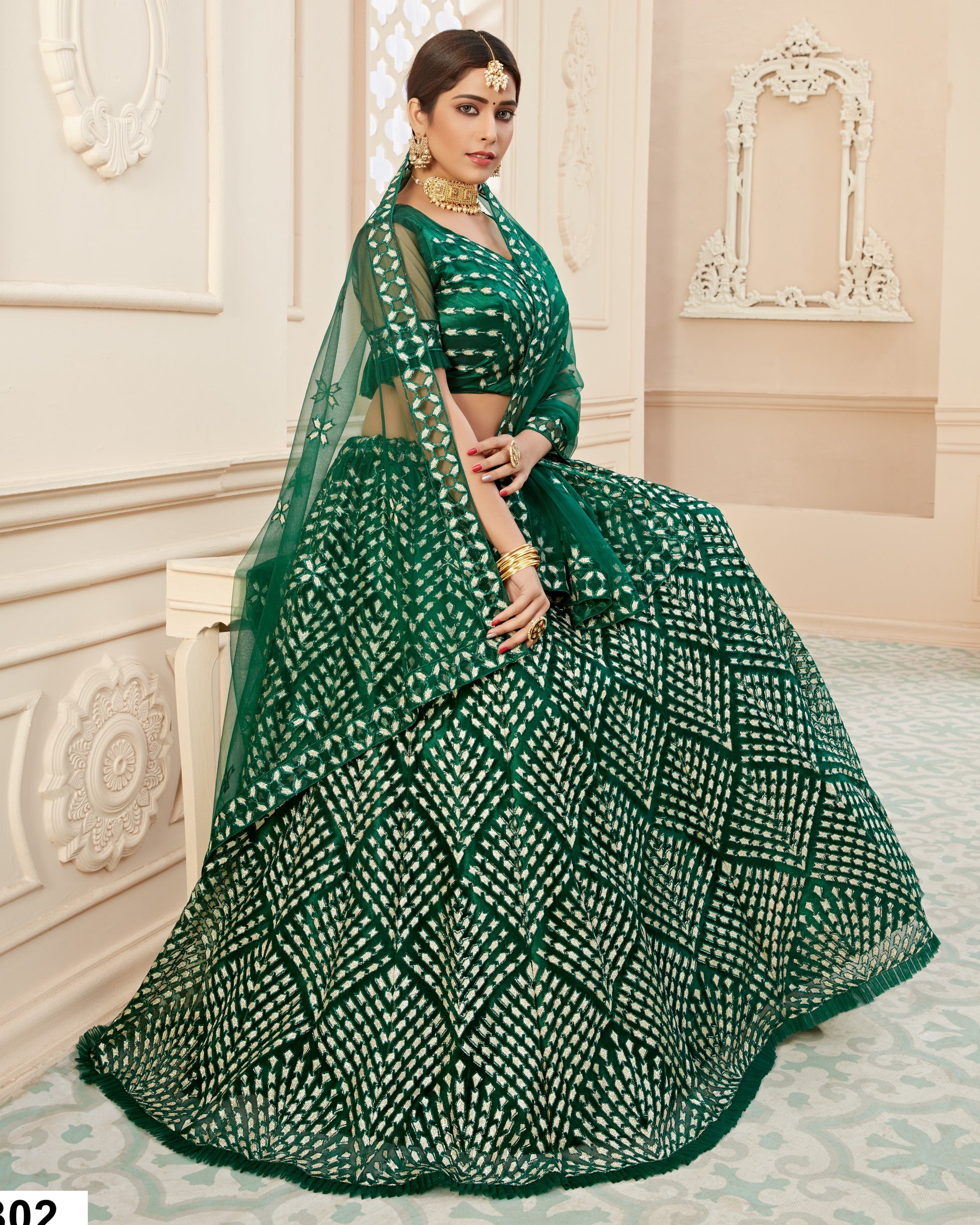 Woman wearing a green and white patterned saree in an elegant room.