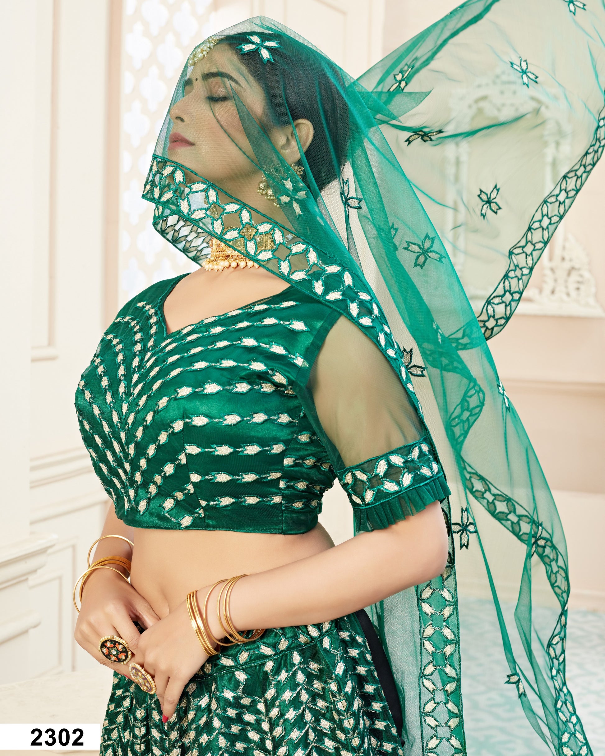 Woman wearing a green saree with a matching dupatta in a well-lit room.
