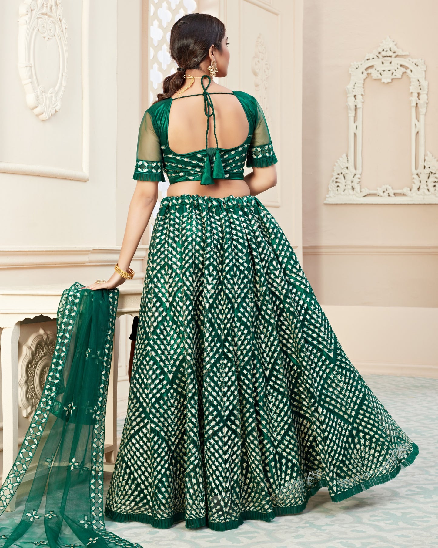 Woman wearing a green and white patterned saree in an elegant interior setting