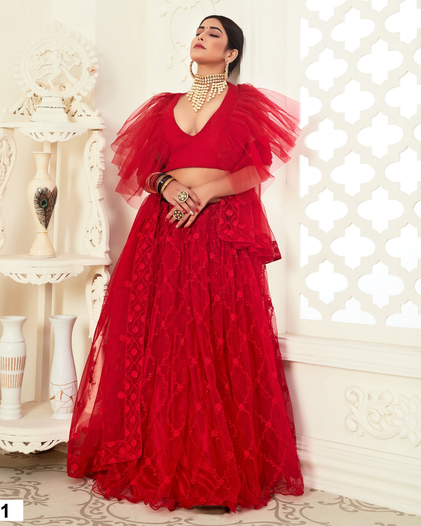 Woman wearing a red outfit with a textured top and flowing skirt in an elegant interior setting.