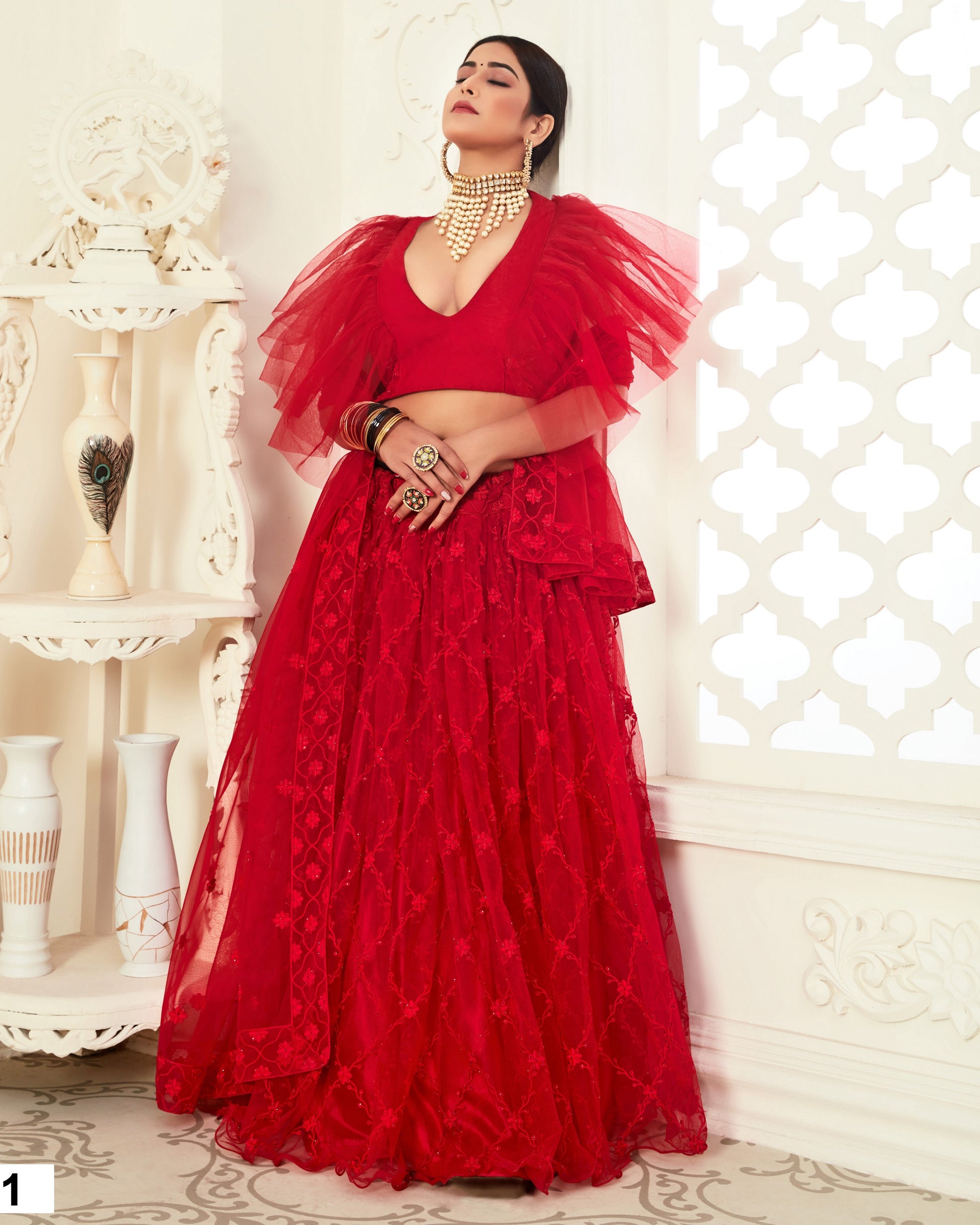Woman wearing a red outfit with a textured top and flowing skirt in an elegant interior setting.