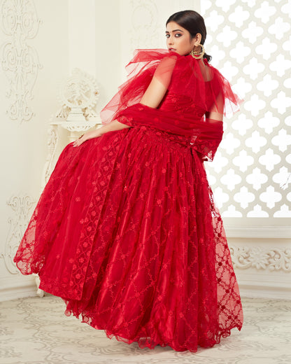 Woman in a red lace dress sitting on a white chair with a decorative white wall background