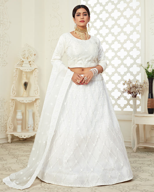 Woman wearing a white traditional outfit with gold jewelry in a decorative room.