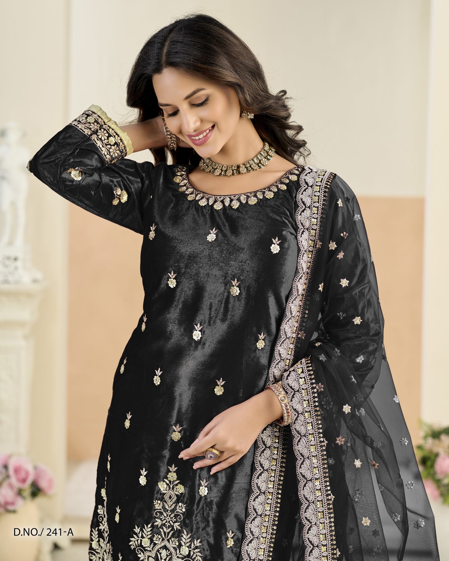 Woman wearing a black embroidered traditional outfit with gold details.