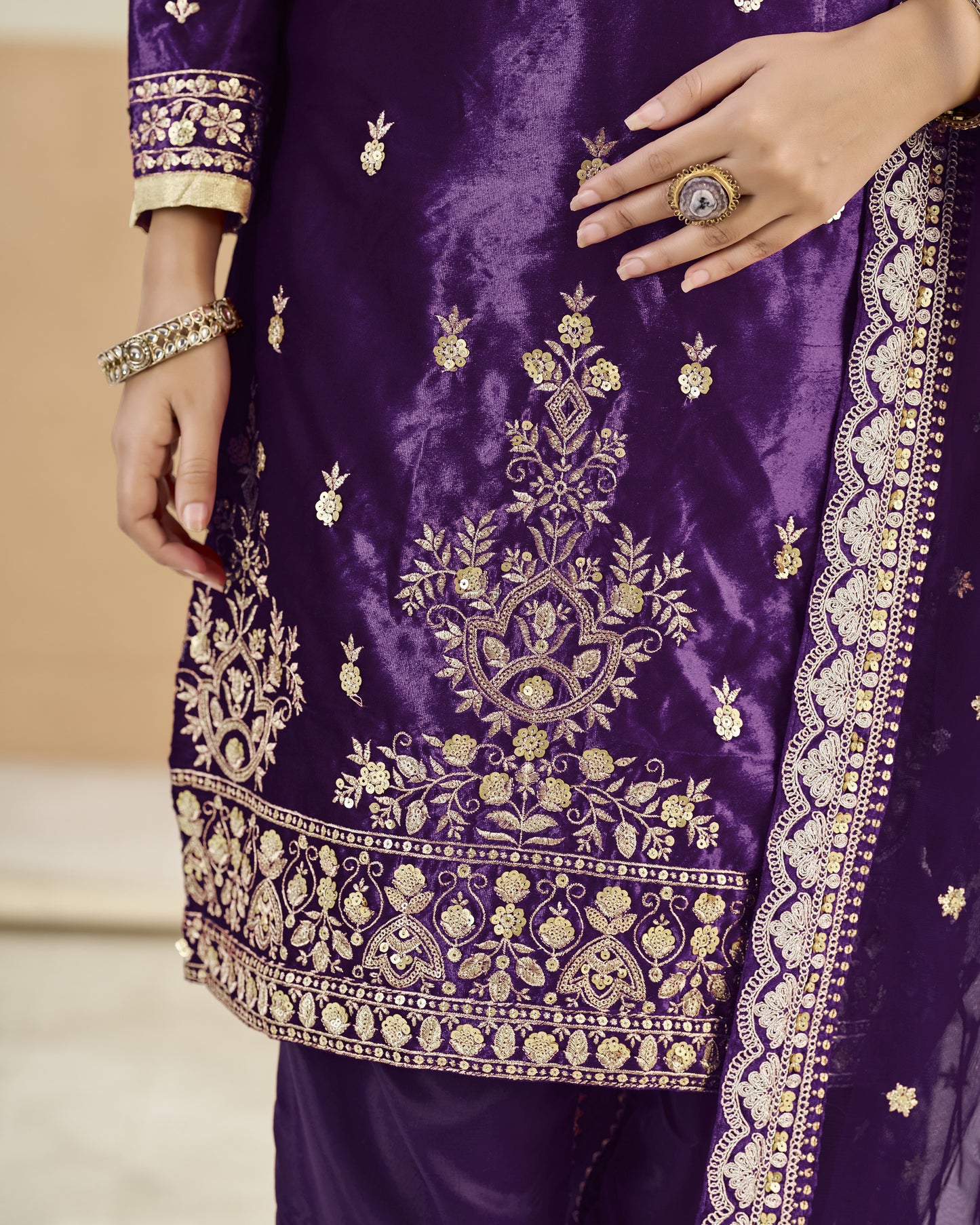 Purple embroidered garment with gold details on a neutral background