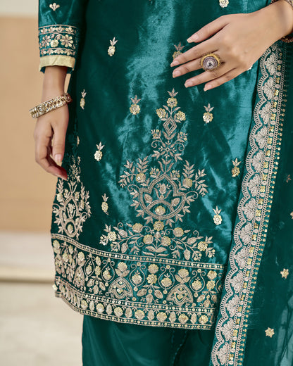 Close-up of a green embroidered garment with intricate patterns and jewelry.
