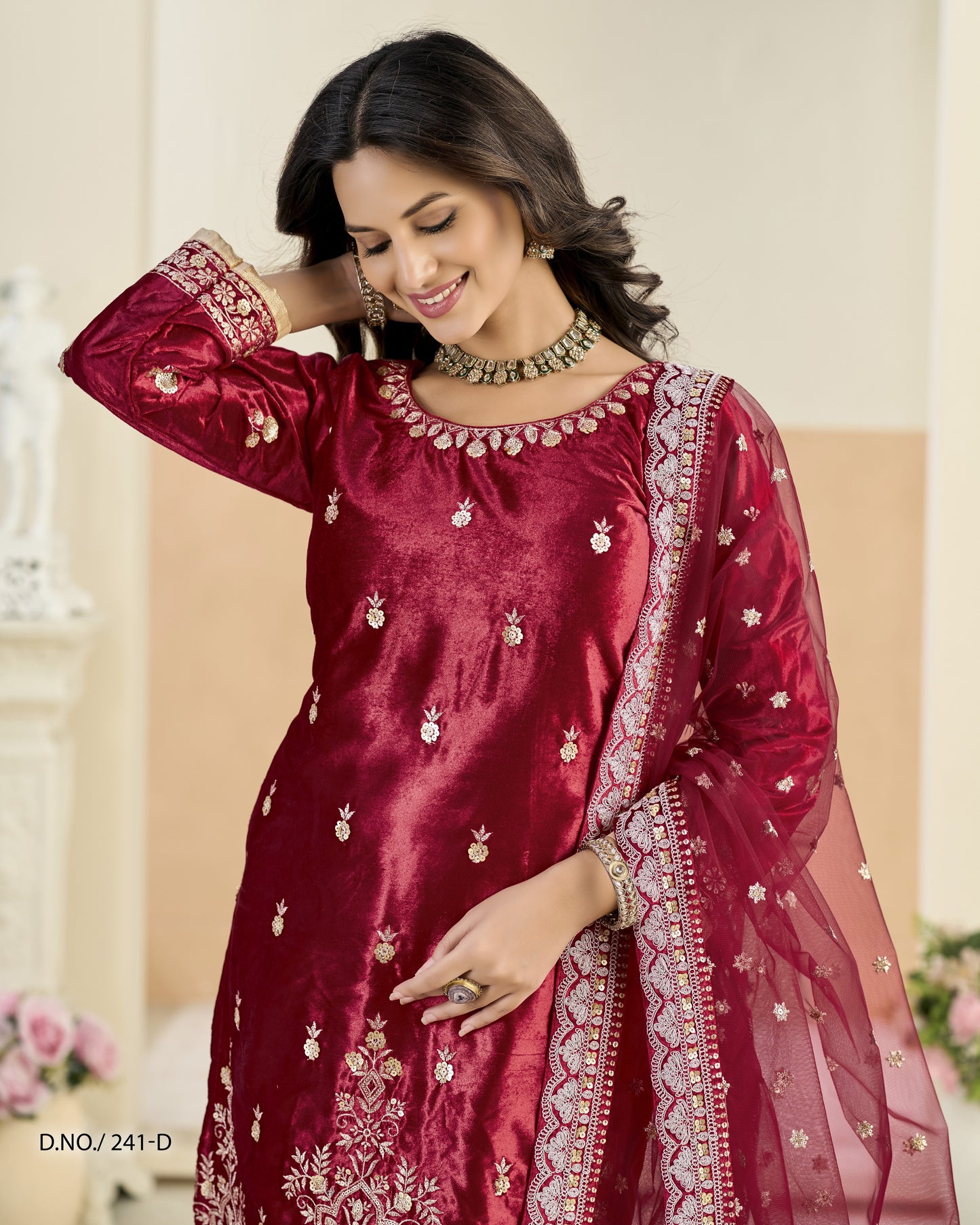 Woman wearing a maroon embroidered traditional outfit with a blurred background