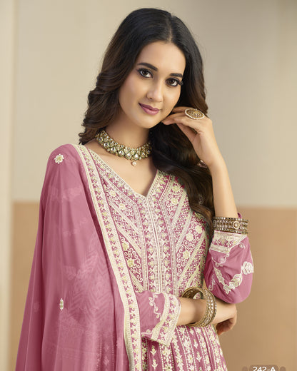 Woman wearing a pink embroidered traditional outfit with jewelry against a beige background